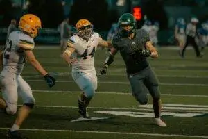 High school football players in action during an evening game under stadium lights.